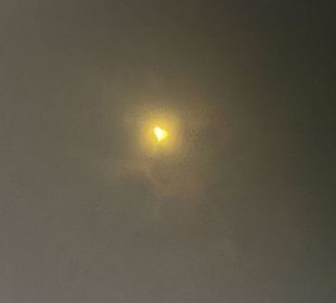 A photo of the April 8, 2024 solar eclipse taken through specialized eclipse-viewing glasses. The sun looks like a heart.