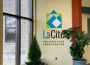 Potted plants sit on the floor by the wall sign for La Cité.