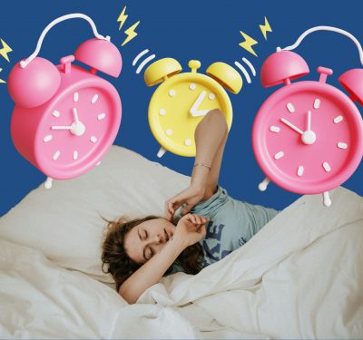 A photo of a person in bed, with several alarm clocks going off in the background.