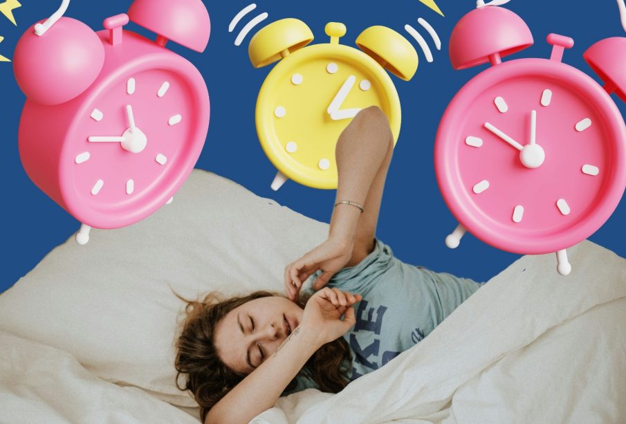 A photo of a person in bed, with several alarm clocks going off in the background.
