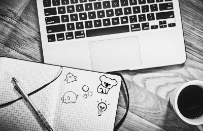 A sketch of an open notebook with doodles, resting on a laptop.