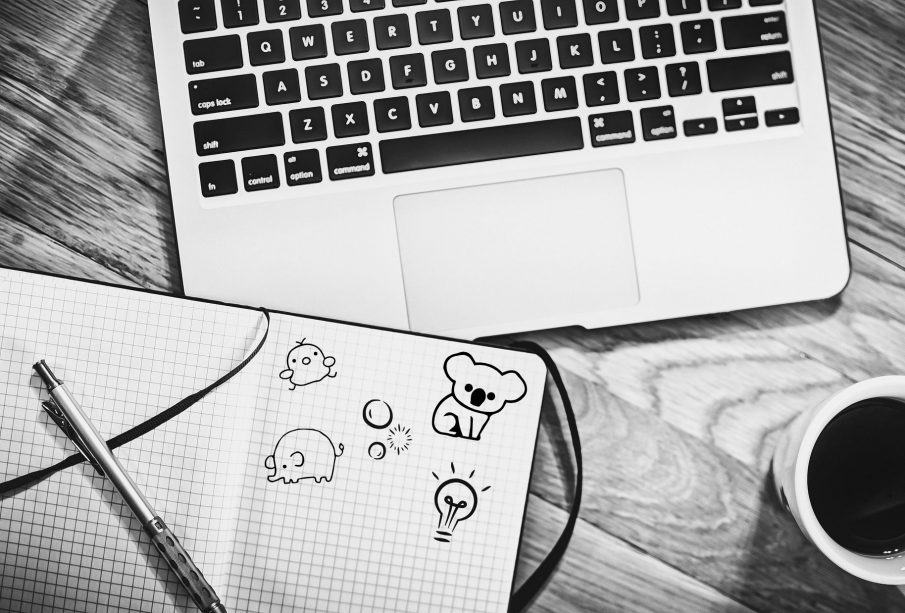 A sketch of an open notebook with doodles, resting on a laptop.