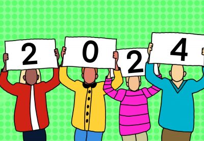 Four individuals in winter-type clothing hold up cards that form the number 2024.