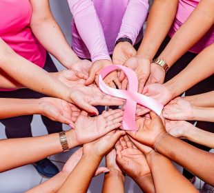 Many people hold a pink breast cancer ribbon.
