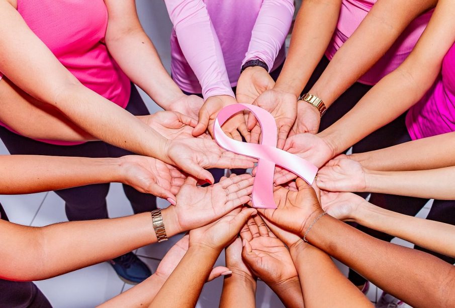 Many people hold a pink breast cancer ribbon.