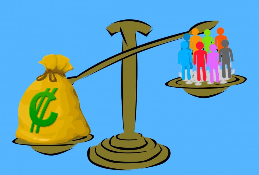An image of a scale that’s weighing a bag of money and a group of people, the bag of money outweighing the group of people.