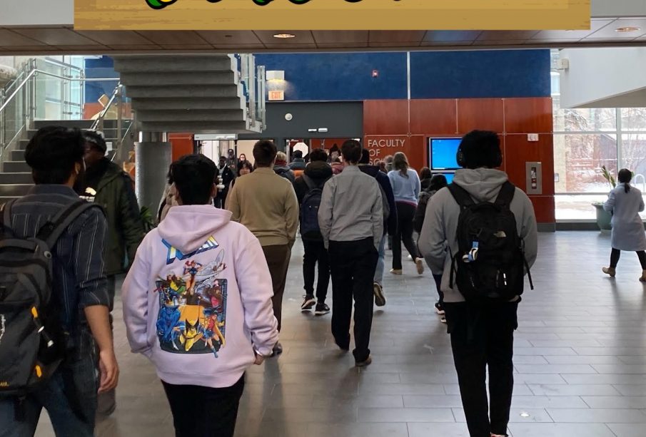 A group of students walk away from the viewer inside a large building