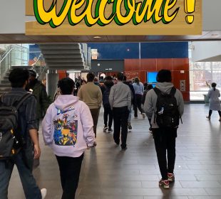 A group of students walk away from the viewer inside a large building