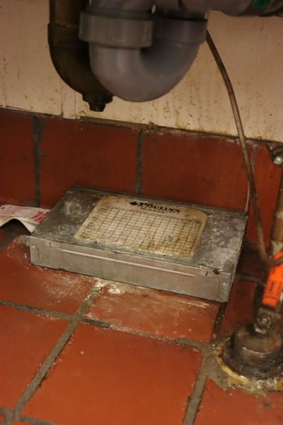 A Poulin’s Pest Control device and sticky trap sit underneath a sink.