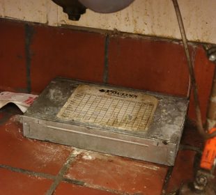 A Poulin’s Pest Control device and sticky trap sit underneath a sink.