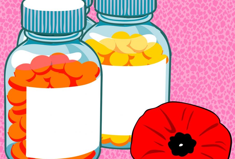 Three unlabelled, full pill bottles sitting beside a poppy flower.