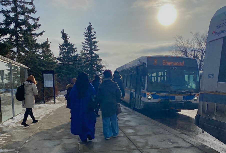 A photo of the Riddell Centre bus stop, with people lined up to board their buses