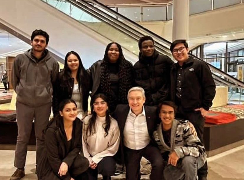 A group photo of several students with the Minister, everyone smiling.