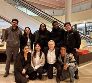 A group photo of several students with the Minister, everyone smiling.
