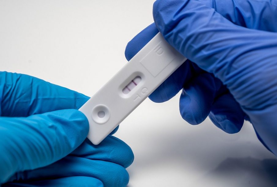 A positive COVID-19 test held in two blue-gloved hands.