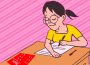 A student taking a paper exam with a red answer sheet on their desk. 