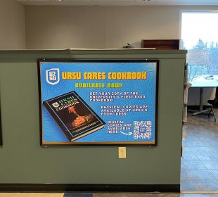  A photo of the URSU Cares Cookbook promotional poster found on the second floor of the Ridell Centre by the URSU front desk. There is a QR code on the bottom right of the poster that links to the online version of the cookbook.