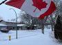 A Canada flag outside in the winter, billowing in the wind.
