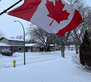 A Canada flag outside in the winter, billowing in the wind.