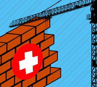 A section of a brick wall with a first aid sign on its front. A solid black silhouette of a crane is lifting the brick wall.