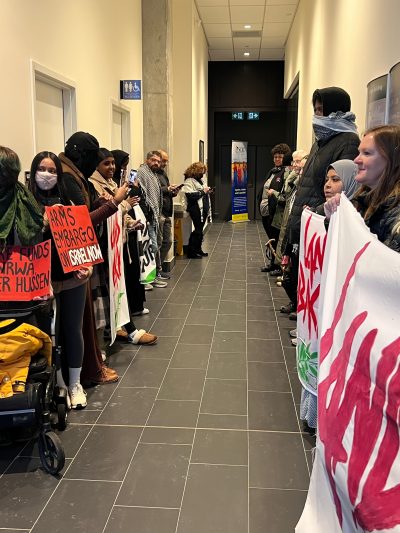 Two rows of protestors for Palestine line either side of a hallway.