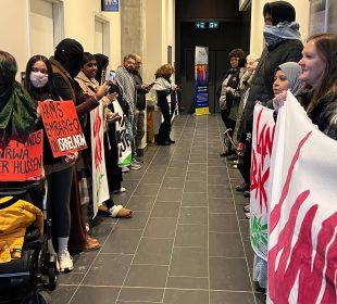 Two rows of protestors for Palestine line either side of a hallway. 
