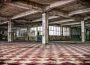An abandoned building sits empty. Graffiti can be seen inside of it, and paint is peeling off of the ceiling.