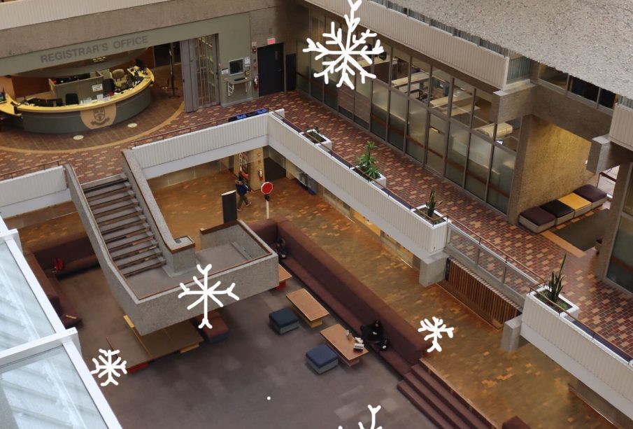 The Administration Humanities conversation pit is pictured from the fifth floor of the building. White snowflakes are drawn overtop the photo and are falling into the pit from the fifth floor. 