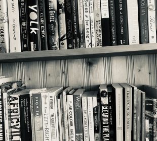 A black and white photograph of a bookshelf with two full shelves. The top shelf includes Thrust by Lidia Yuknavitch; Vita Nostra by Marina and Sergey Dyachenko; A Little Life by Hanya Yanaghihara; The Wolf Den by Elodie Harper; Hamnet by Maggie O’Farrell; The Secret History by Donna Tartt; My Year of Rest and Relaxation by Ottessa Moshfegh; White on White by Ayşegül Savaş; Big Swiss by Jen Beagin; Across a Hundred Mountains by Reyna Grande; Piranesi by Susanna Clarke; Jawbone by Mónica Ojeda; Intimacies by Katie Kitamura; This Vicious Grace by Emily Thiede; Woman, Eating by Claire Kohida; Yolk by Mary H.K. Choi; Stone Blend by Natalie Haynes; The Goldfinch by Donna Tartt; and Fourth Wing by Rebecca Yarros. The second shelf holds Gate 7 by manga artist group Clamp; Cabin Porn by Little, Brown and Company; Chromophobia by David Batchelor; Summer 2020 Ecology Issue No. 41 of Qwerty; Spring 2023 Issue No. 295 of The Fiddlehead; Transforming Power by Judy Rebick; Determinants of Indigenous Peoples’ Health Second Edition by Greenwood, de Leeuw, and Lindsay; Me Tomorrow: Indigenous Views of the Future by Douglas & McIntyre; Clearing The Plains by James William Daschuk; The Communist Manifesto by Marx and Engels; Saskatchewan Dirt: A Pandemic Quest for Connection by Bev Lundahl; Survival of the Friendliest by Brian Hare and Vanessa Woods; Women, Culture, & Politics by Angela Y. Davis; Weeds of Canada and the Northern United States by Royer & Dickinson; Pure Colour by Sheila Heti; Listening to the Beat of our Drum edited by Carrie Bourass, Elder Betty McKenna and Darlene Juschka; Noticed, Known and Missed by Cara Milne; The Power of Disability by Al Etmanski; and From Left to Right: Saskatchewan’s Political and Economic Transformation by Dale Eisler.