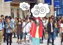 A photo of a person in a mask, in a crowd of other pedestrians. They look nervous and overcome with thoughts.