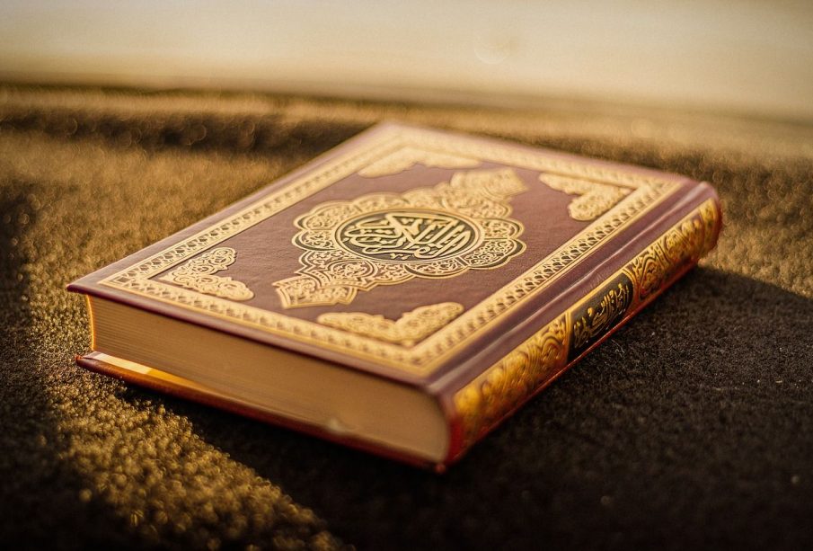 A copy of the Quran sits on a carpet and is illuminated by sunlight