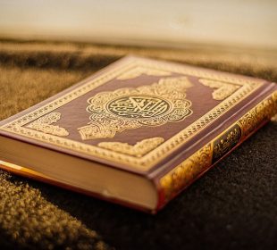 A copy of the Quran sits on a carpet and is illuminated by sunlight