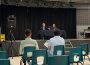 A photo is taken from behind the front row at a town hall with university executives. Jeff Keshen is pictured at a table on the stage.