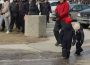 Teachers walk in a large group in front of the Saskatchewan Legislature. In front of them, just off of the sidewalk, two children stand on ice.