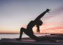 A photo of a person doing yoga outdoors by a lake.