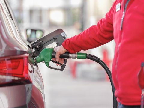 A person’s arm is shown filling up a car tank with fuel.