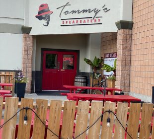 The entrance to Tommy’s Speakeatery, with a graphic of a head’s silhouette and a bright red fedora