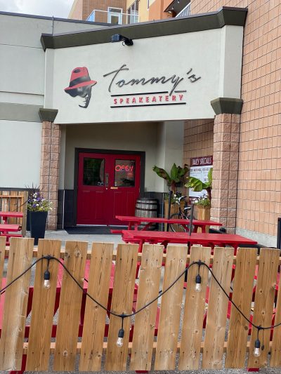 The entrance to Tommy’s Speakeatery, with a graphic of a head’s silhouette and a bright red fedora
