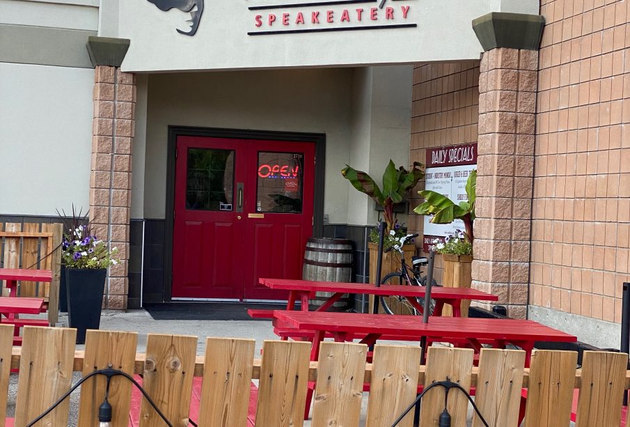 The entrance to Tommy’s Speakeatery, with a graphic of a head’s silhouette and a bright red fedora