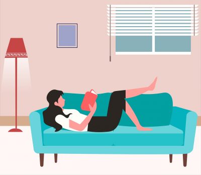 A person lying on a couch, reading a book.