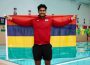 A photo of Ovesh Purahoo holding a flag of his country, Mauritius. He is standing in front of the U of R pool.