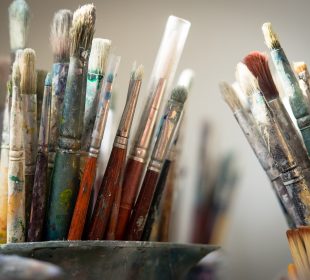 A photo of countless dirty paint brushes.