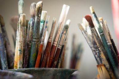A photo of countless dirty paint brushes.