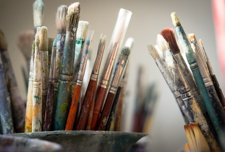 A photo of countless dirty paint brushes.
