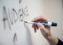 A whiteboard, with a hand holding a marker writing the word “audience.”