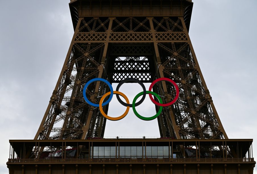 A photo of the Eiffel tower during the 2024 Paris Games. The tower has the 5 Olympic rings logo hung from it.