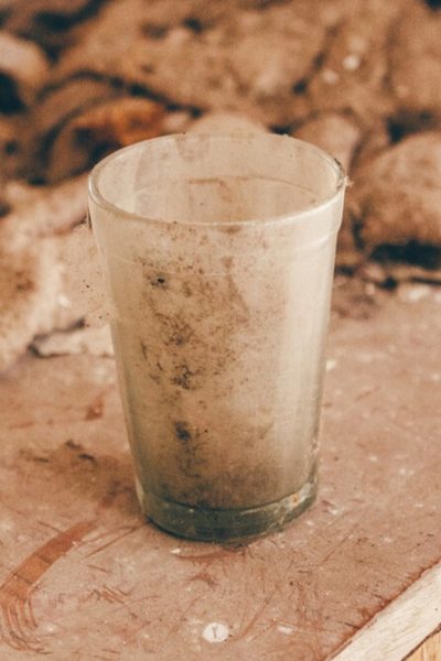 A dirty glass sits on a dusty countertop