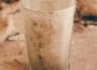 A dirty glass sits on a dusty countertop