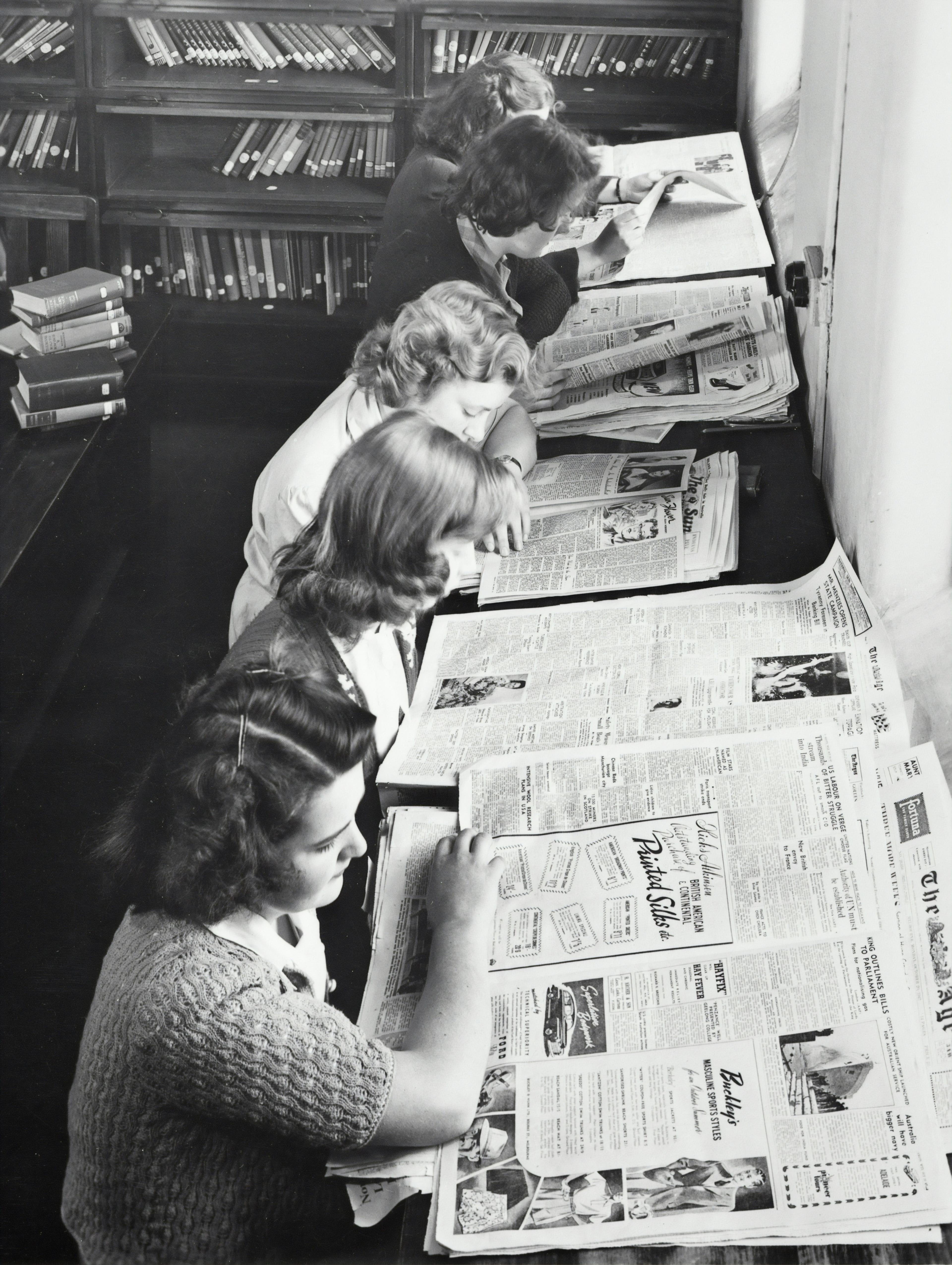 People in a library reading the newspaper.
