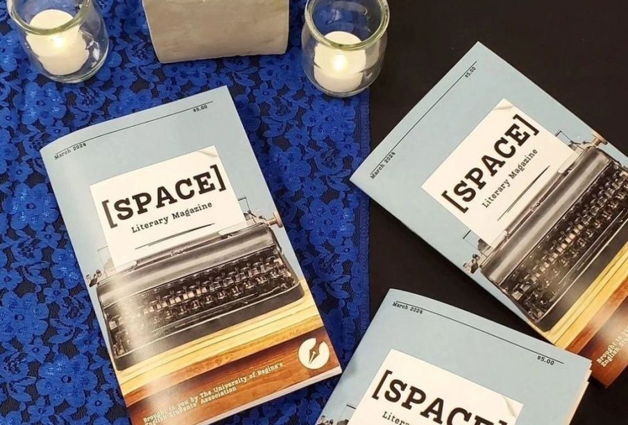 Three [SPACE] magazines laid on a table. A blue lace tablecloth, decorative plant, and two candles are also on the table.